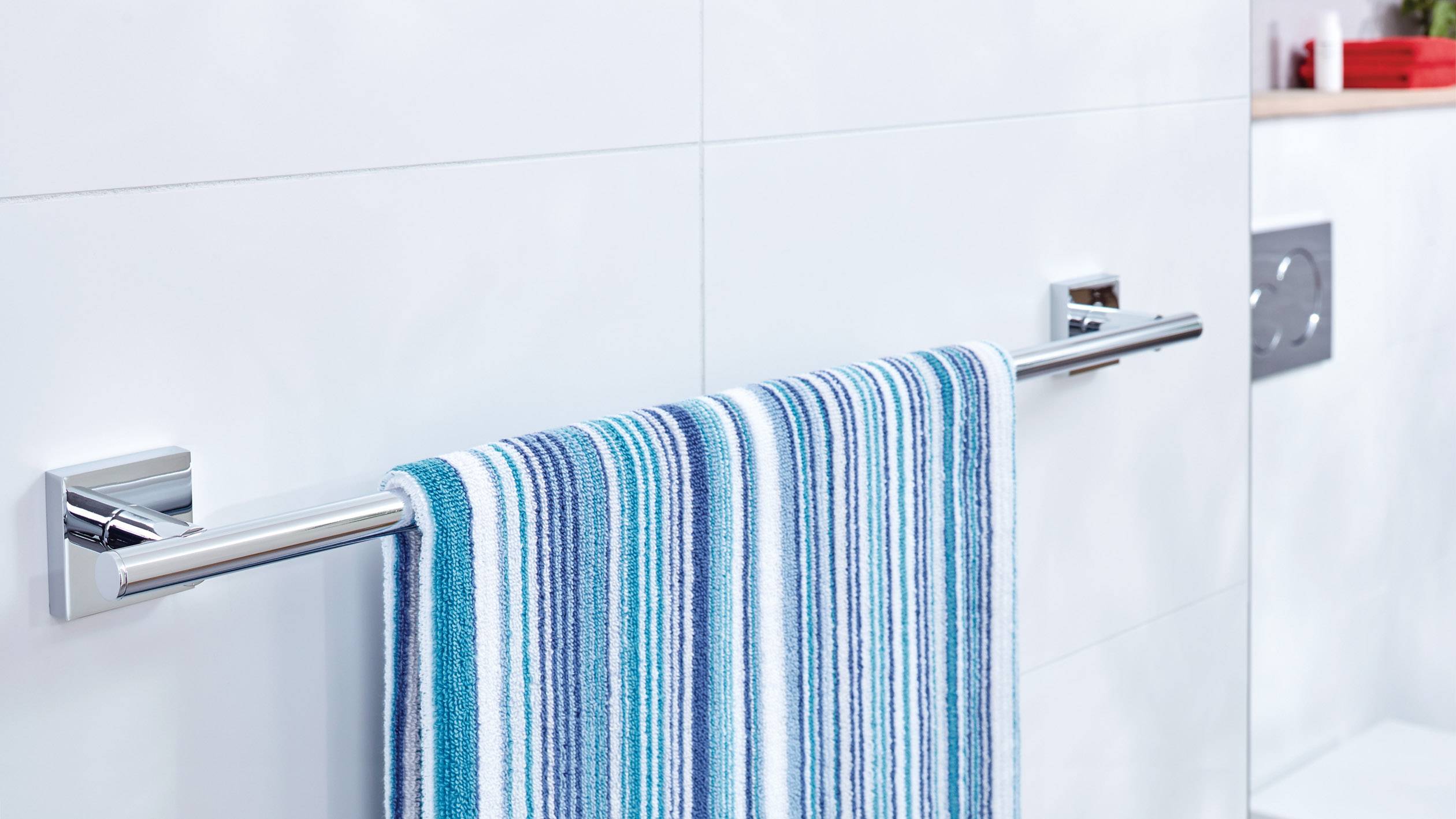 Porte-serviettes avec une serviette rayée bleue, fixée à un mur de salle de bain carrelé de blanc.