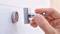 Une main insère une clé dans une serrure moderne sur un mur.