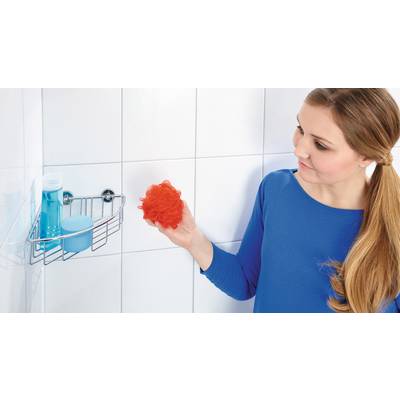Une femme portant un haut bleu tient une éponge de douche rouge à côté de carreaux de salle de bain.