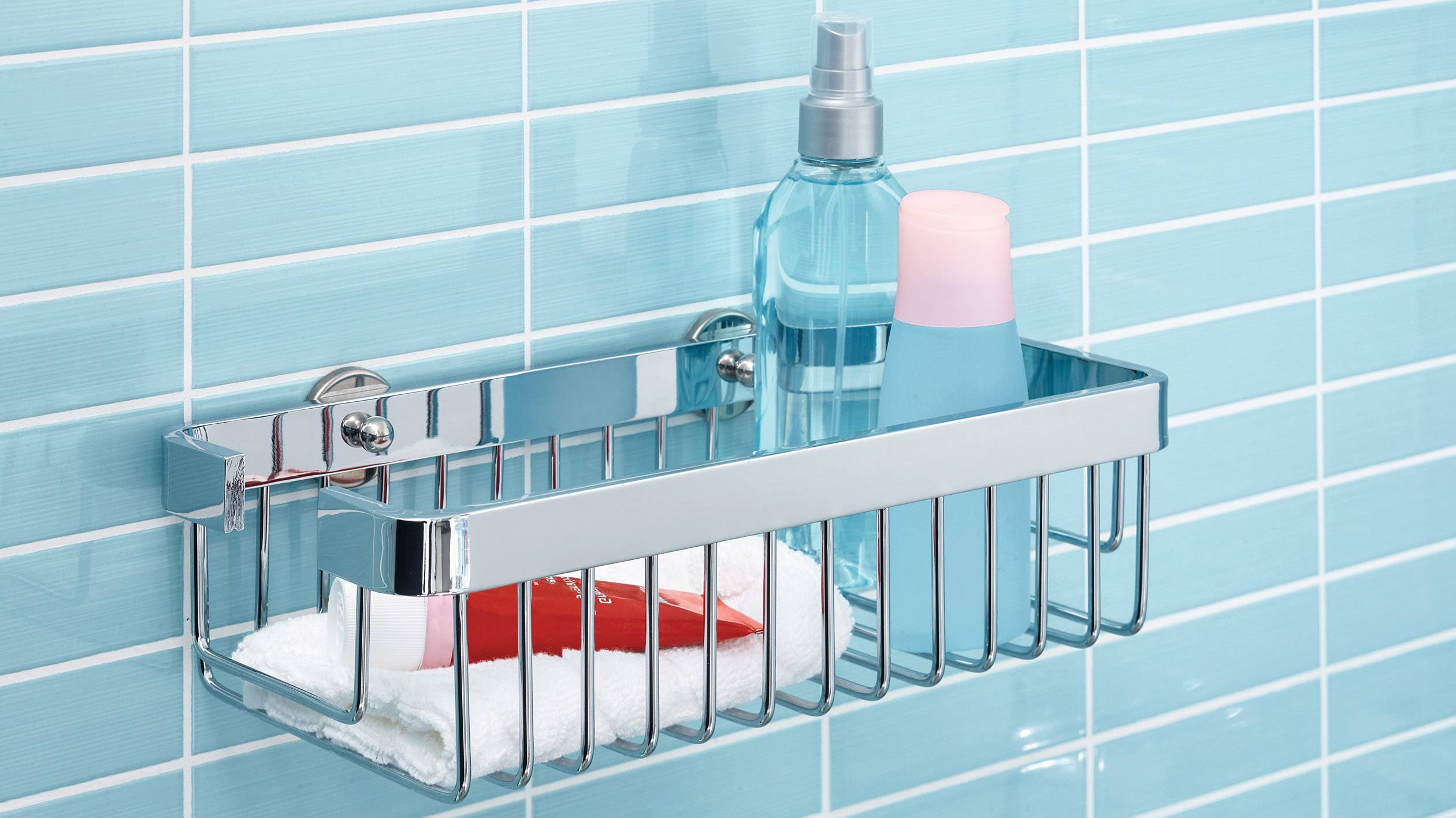 Étagère de douche avec des flacons de shampoing et de produits de soin corporel devant des carreaux bleus ; surface antidérapante en haut.