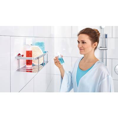Une femme dans la salle de bain tient une bouteille de bain de bouche bleue. À côté d'elle se trouvent des produits de soin sur une étagère de douche.