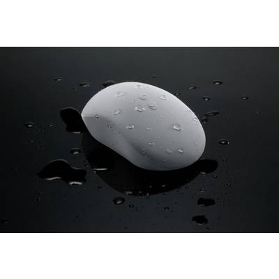 Un savon blanc ovale est posé sur une surface brillante et humide. Des gouttelettes d'eau sont visibles sur le savon et tout autour.