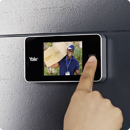 Une personne pose son doigt sur un lecteur d'empreinte digitale près d'une porte. Un écran affiche une image d'un livreur de colis.