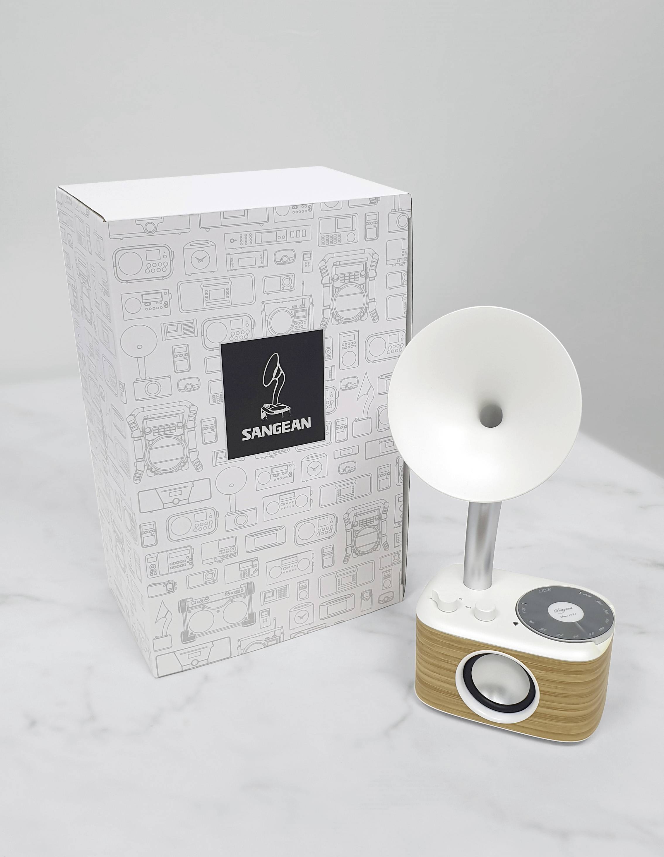 Un haut-parleur rétro à trompette est posé à côté d'un emballage de Sangean. Le design combine un aspect bois avec des détails modernes.