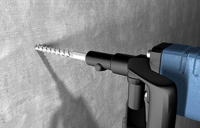 Une perceuse bleue fore un mur en béton avec un long foret.
