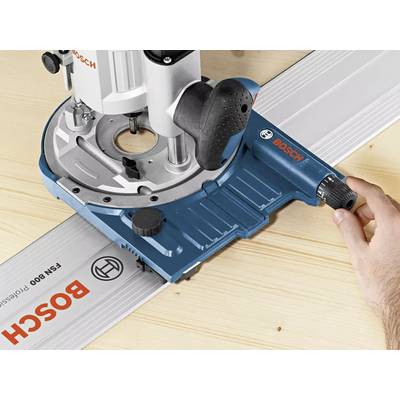 Une main guide une fraiseuse Bosch le long d'un rail de guidage sur une surface en bois.