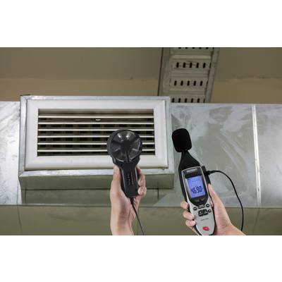 Une personne tient un sonomètre devant une bouche de ventilation, qui affiche une valeur de 46,8 décibels.