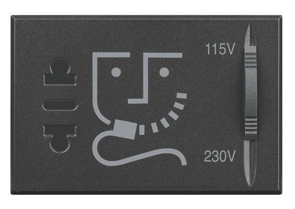 Adaptateur noir et gris avec indication 115V et 230V, comprenant un schéma stylisé d'un visage souriant et différentes formes de fiches électriques.