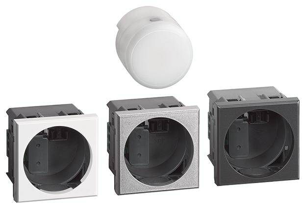 Trois modules de prises électriques carrés en blanc, argent et noir, avec un couvercle rond blanc à côté des modules.