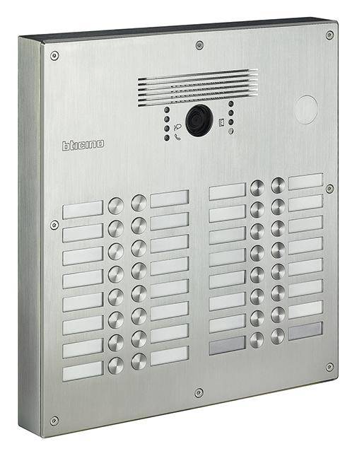 Interphone avec caméra et haut-parleur, boîtier en acier inoxydable, de nombreux boutons de noms sur une plaque structurée.