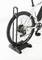 Un vélo blanc est posé sur un support de vélo noir qui stabilise la roue arrière. L'accent est mis sur le pneu et la structure du support.