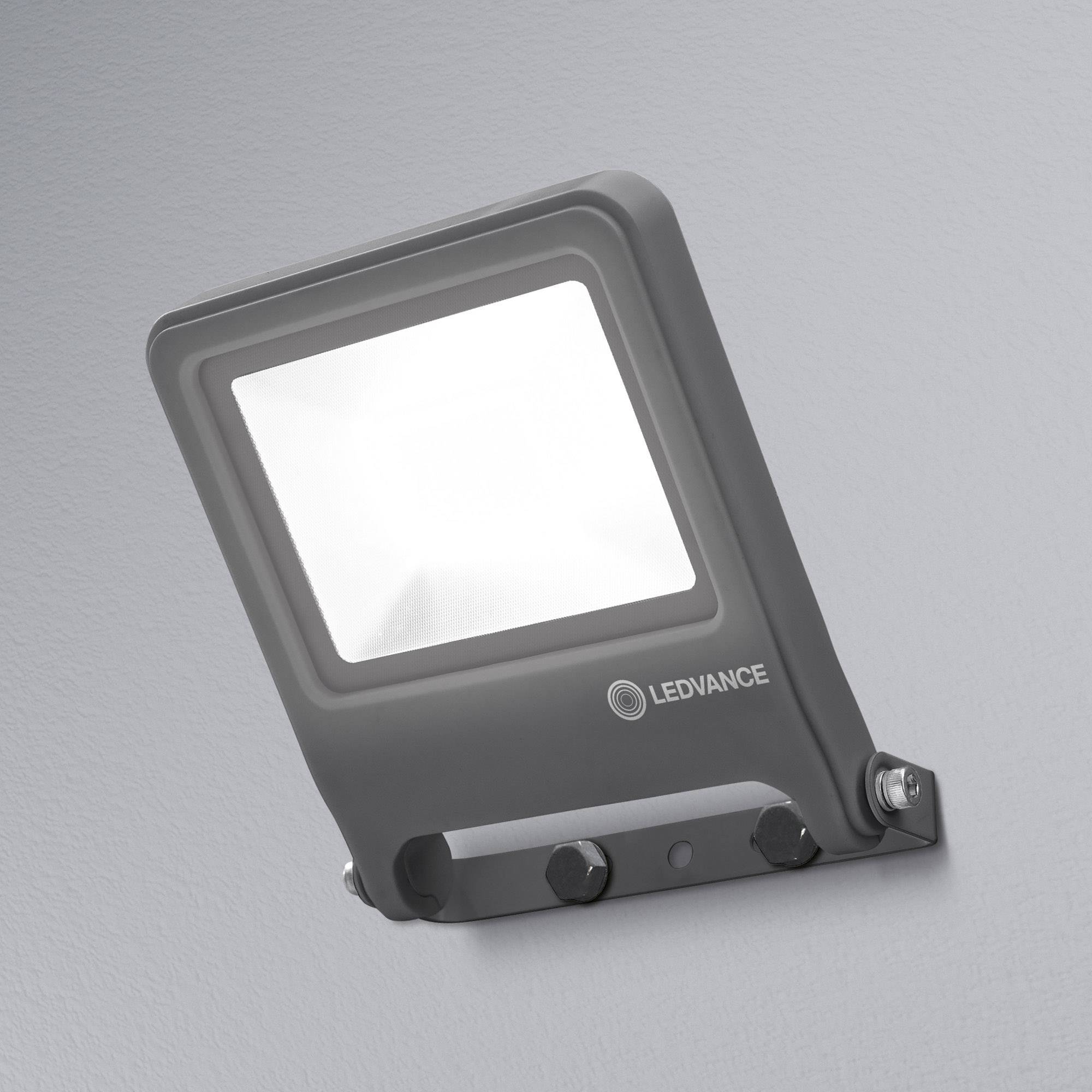 Un projecteur LED gris avec un faisceau lumineux intense, monté sur un mur. En dessous, le logo et le nom 'LEDVANCE'.