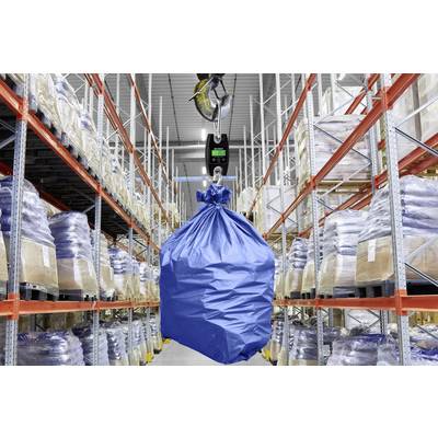 Un sac bleu est soulevé par une grue avec une balance numérique dans un entrepôt. Des étagères avec des cartons et des sacs sont visibles en arrière-plan.