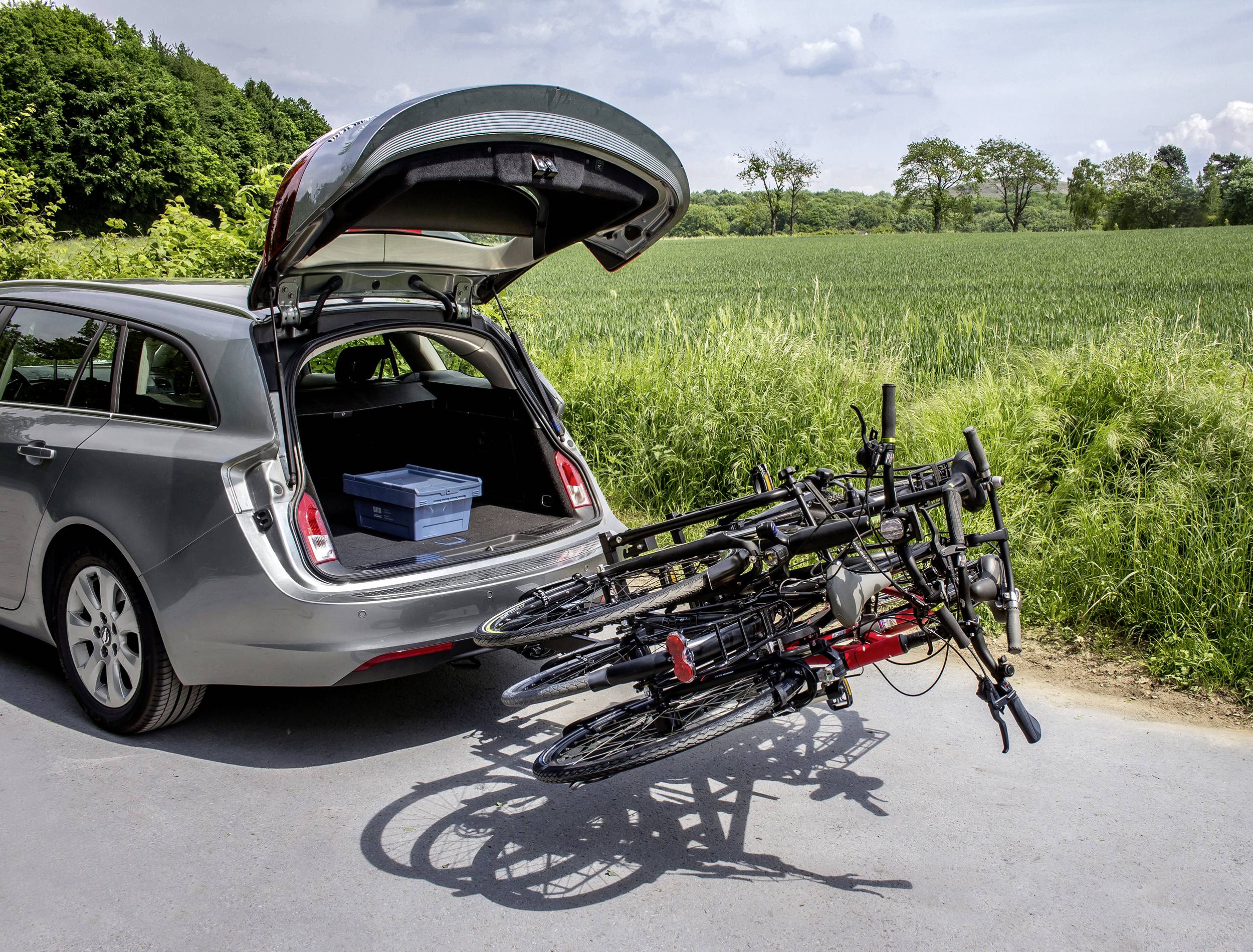 Une voiture avec le hayon ouvert est garée sur une route. Deux vélos sont fixés sur un porte-vélos à l'arrière du véhicule.