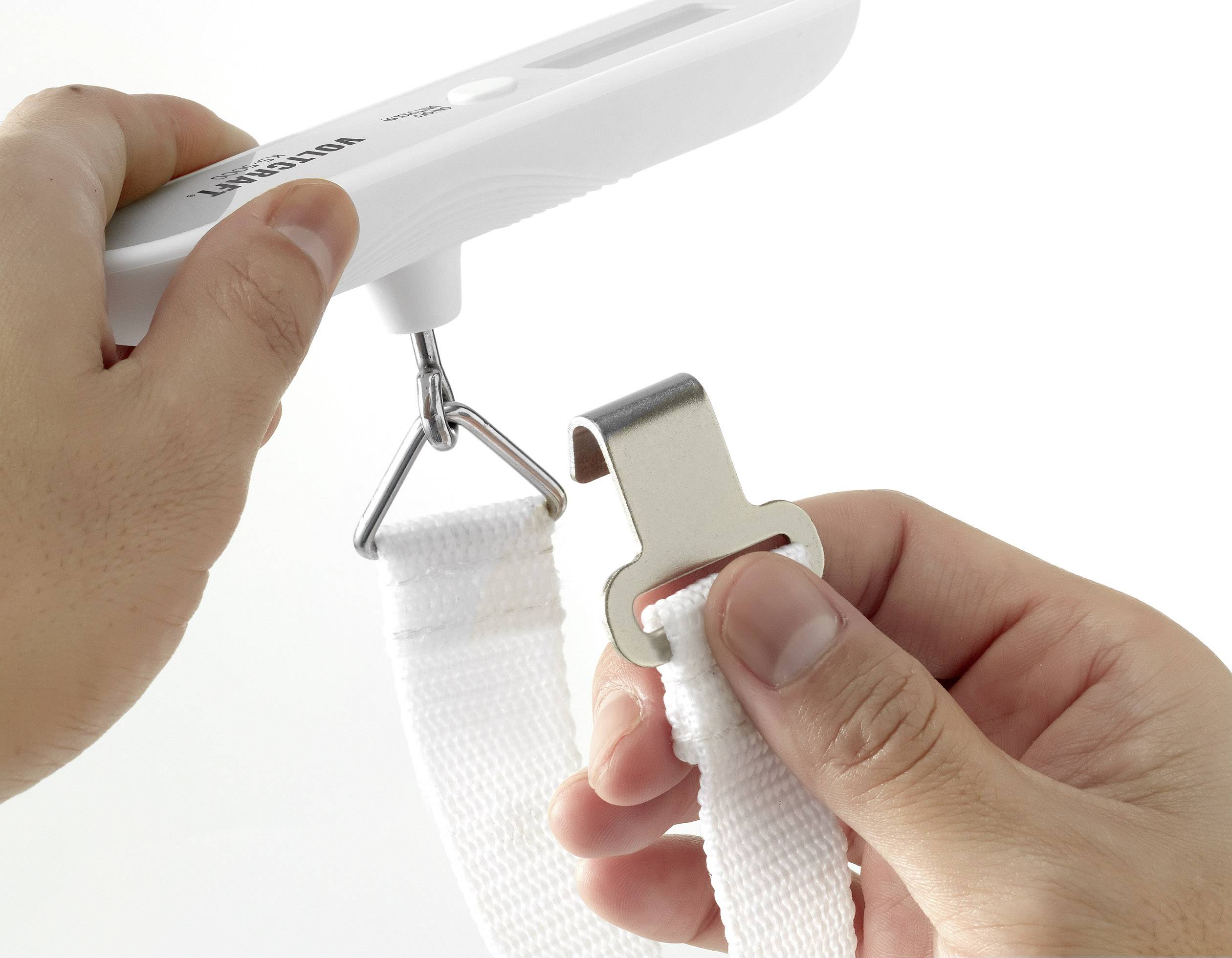Une personne tient et présente un pèse-bagage portable avec un crochet fixé à une sangle blanche.