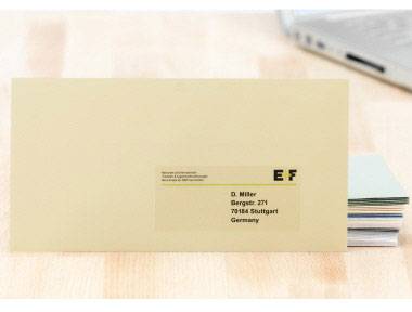 Enveloppe avec étiquette d'adresse, adressée à 'D. Müller, Bergerstr. 27, 70184 Stuttgart, Allemagne', posée sur une table.