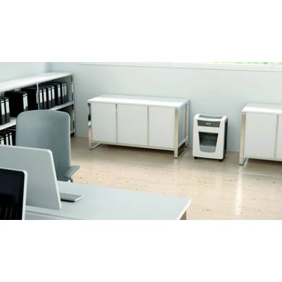 Un bureau lumineux avec un sol en bois, un bureau, une étagère contenant des classeurs et un destructeur de documents dans le coin.