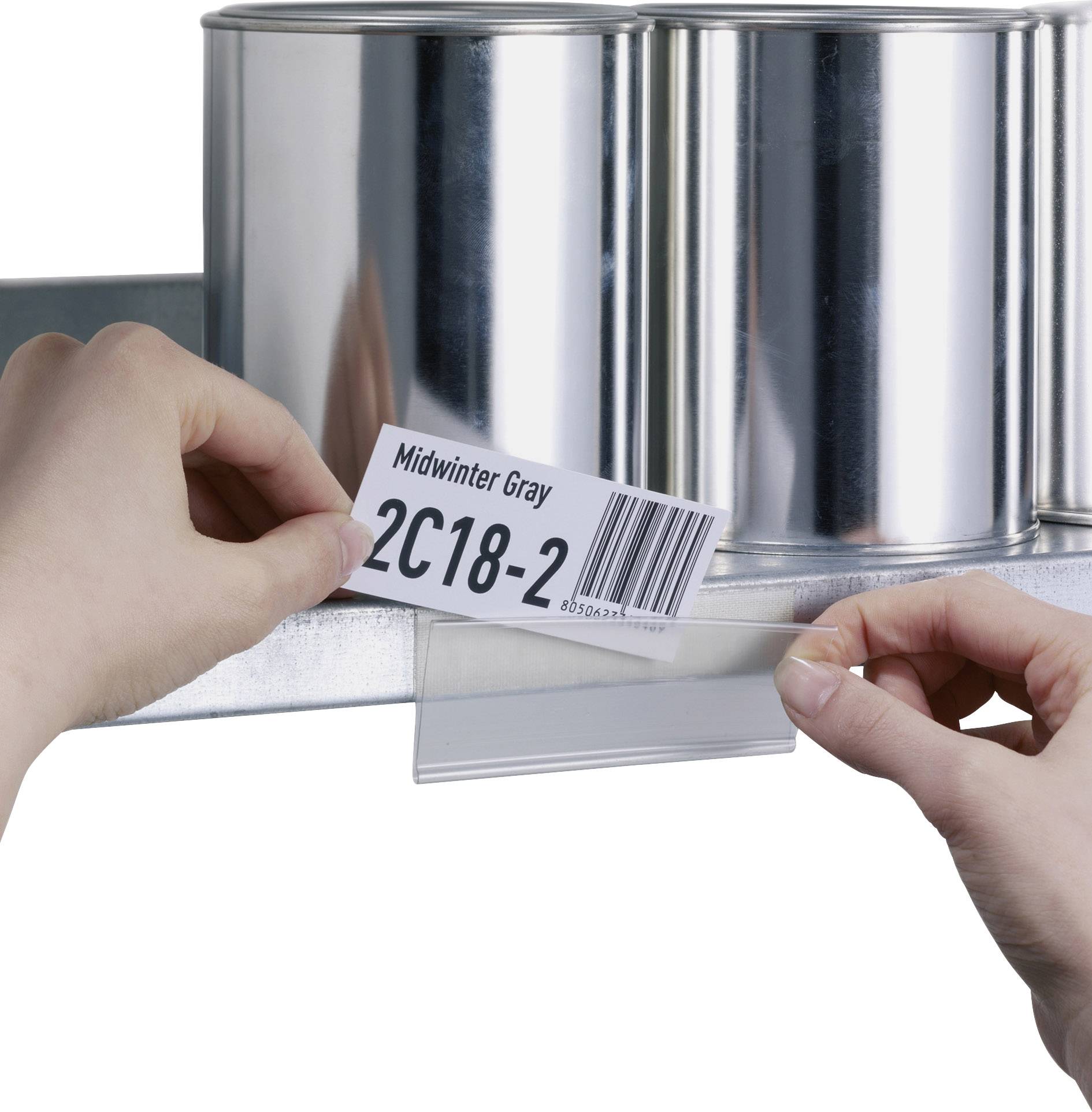 Une personne étiquette une étagère métallique avec une étiquette portant l'inscription 'Midwinter Gray 2C18-2'. Des contenants métalliques sont visibles en arrière-plan.