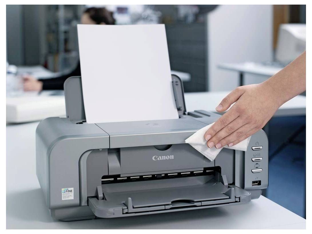 « Une imprimante en train d'être nettoyée avec un chiffon par la main d'une personne dans un bureau. »