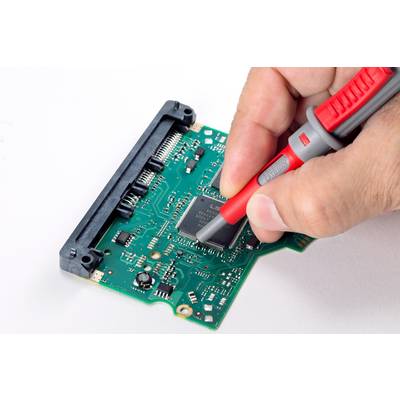 Une main tient une sonde de test et touche les circuits sur une carte électronique verte qui est installée dans un ordinateur.