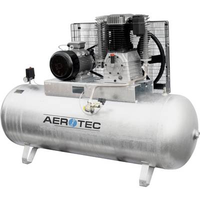 Un grand compresseur d'air argenté avec le logo 'AEROTEC' sur le réservoir, relié à un moteur électrique d'alimentation au-dessus.