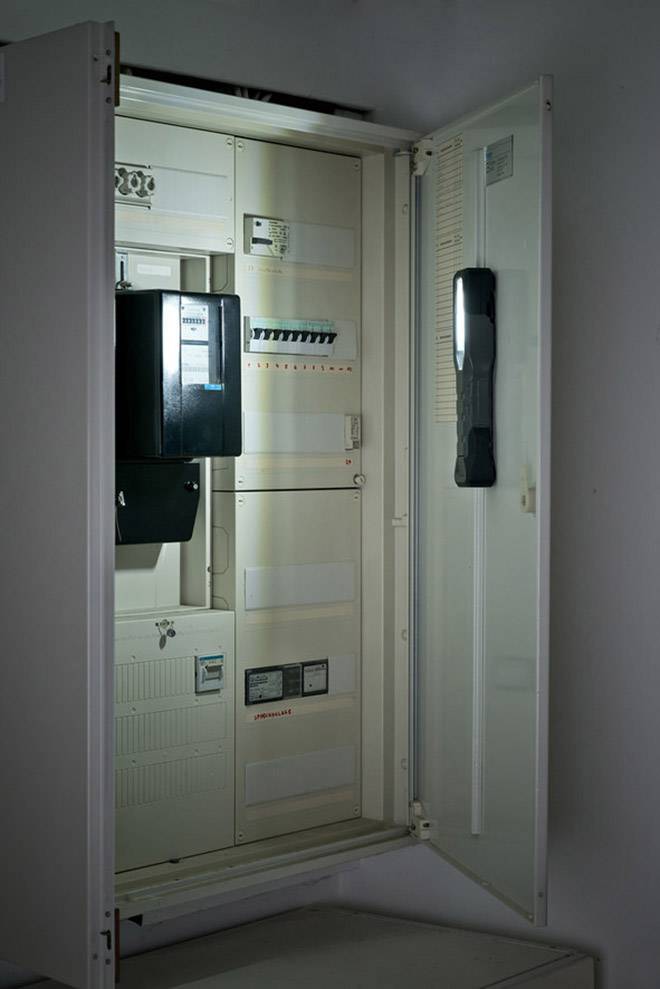 Un armoire électrique ouvert montre plusieurs composants électriques et interrupteurs. La porte est ouverte vers la droite et la lumière tombe sur sa surface intérieure.