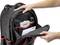 Une personne ouvre la partie avant d'un sac à dos noir avec des accents rouges, révélant des poches et des compartiments remplis.