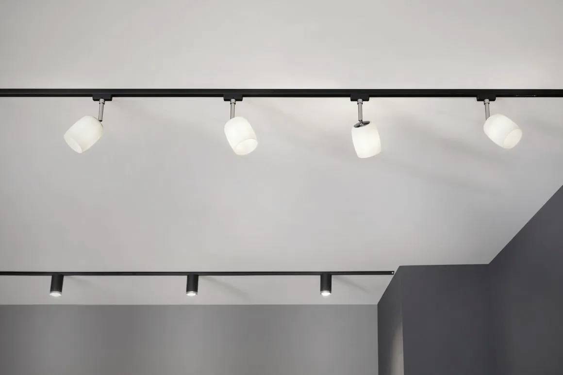 Cuisine moderne avec îlot central, sol en bois et grande fenêtre panoramique offrant une vue sur la ville. Placards sombres, lampes suspendues, décoration minimaliste.