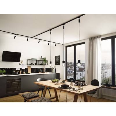Cuisine moderne avec espace repas ouvert, sol en bois, grande table, lampes suspendues et fenêtre offrant une vue sur le paysage urbain.