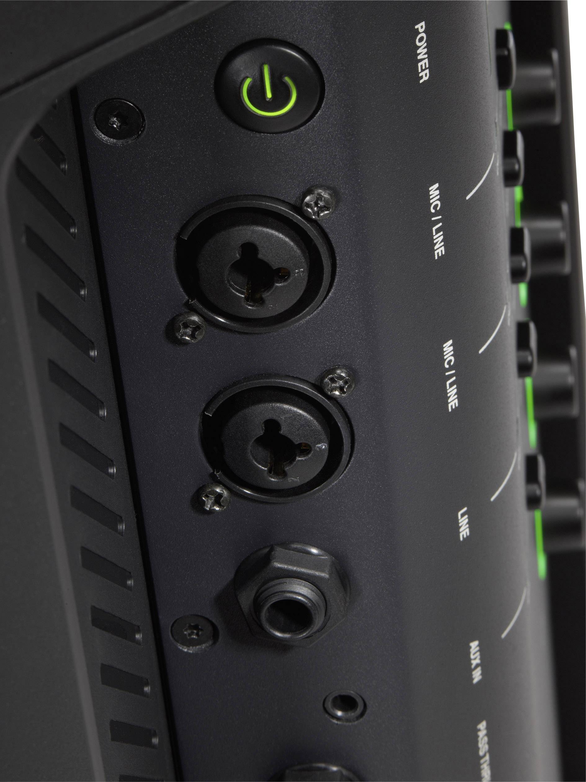 Gros plan sur un amplificateur audio noir avec plusieurs connexions et un bouton de mise en marche vert illuminé.