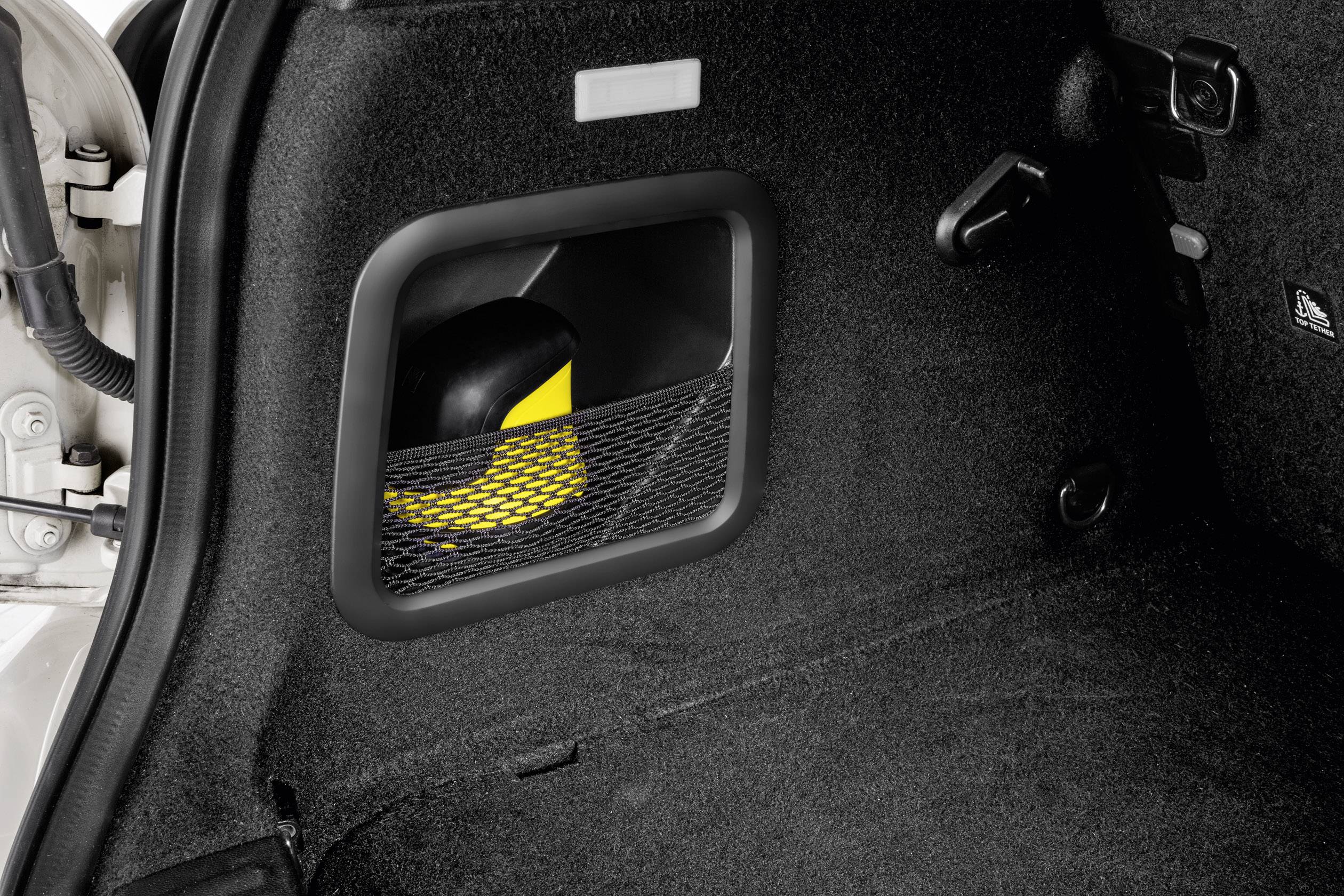 Une vue latérale du coffre d'une voiture avec un espace de rangement sécurisé par un filet. Contient un objet jaune et noir.
