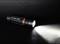 La lampe de poche brille dans un espace sombre. Elle est noire avec un anneau rouge et l'inscription 'AccuLux 200L'.