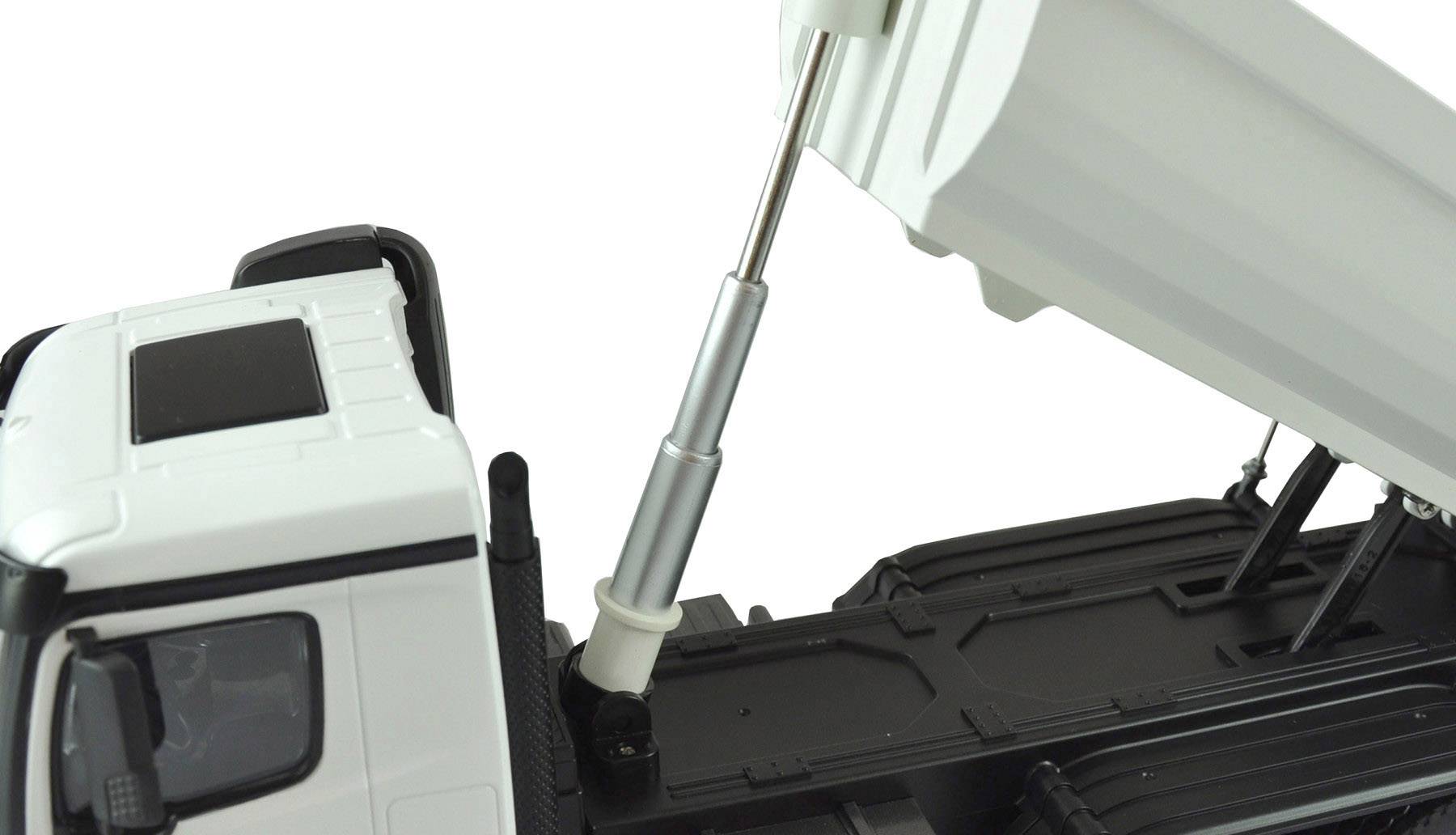 Un camion blanc avec un mécanisme de benne basculante ouvert montre le vérin hydraulique en action. La structure est noire.