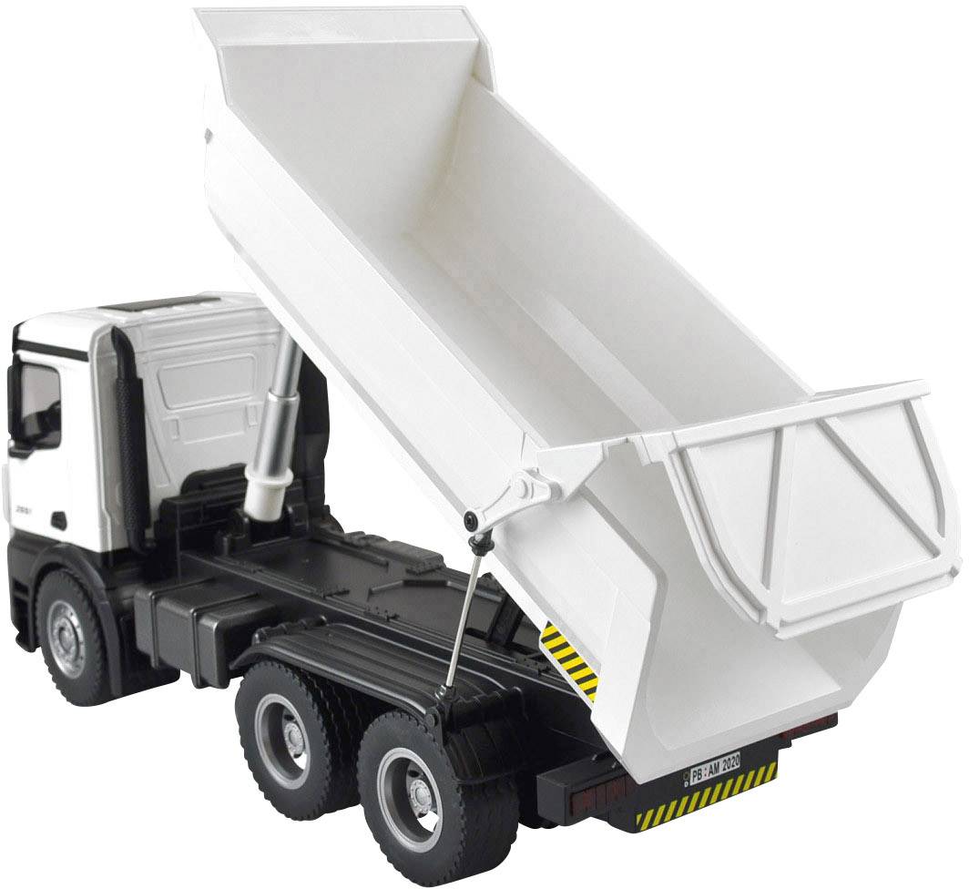 Camion-jouet avec une surface de chargement basculante, représenté en blanc et noir, sur un fond blanc. La surface de chargement montre un mouvement de bascule.