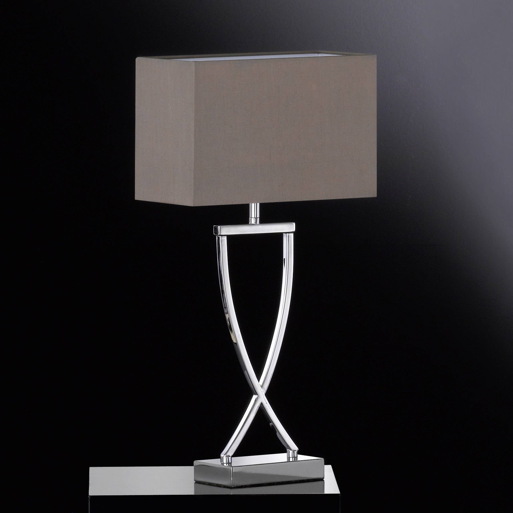 Une lampe de table moderne avec un abat-jour rectangulaire brun et un socle incurvé argenté sur un fond noir.