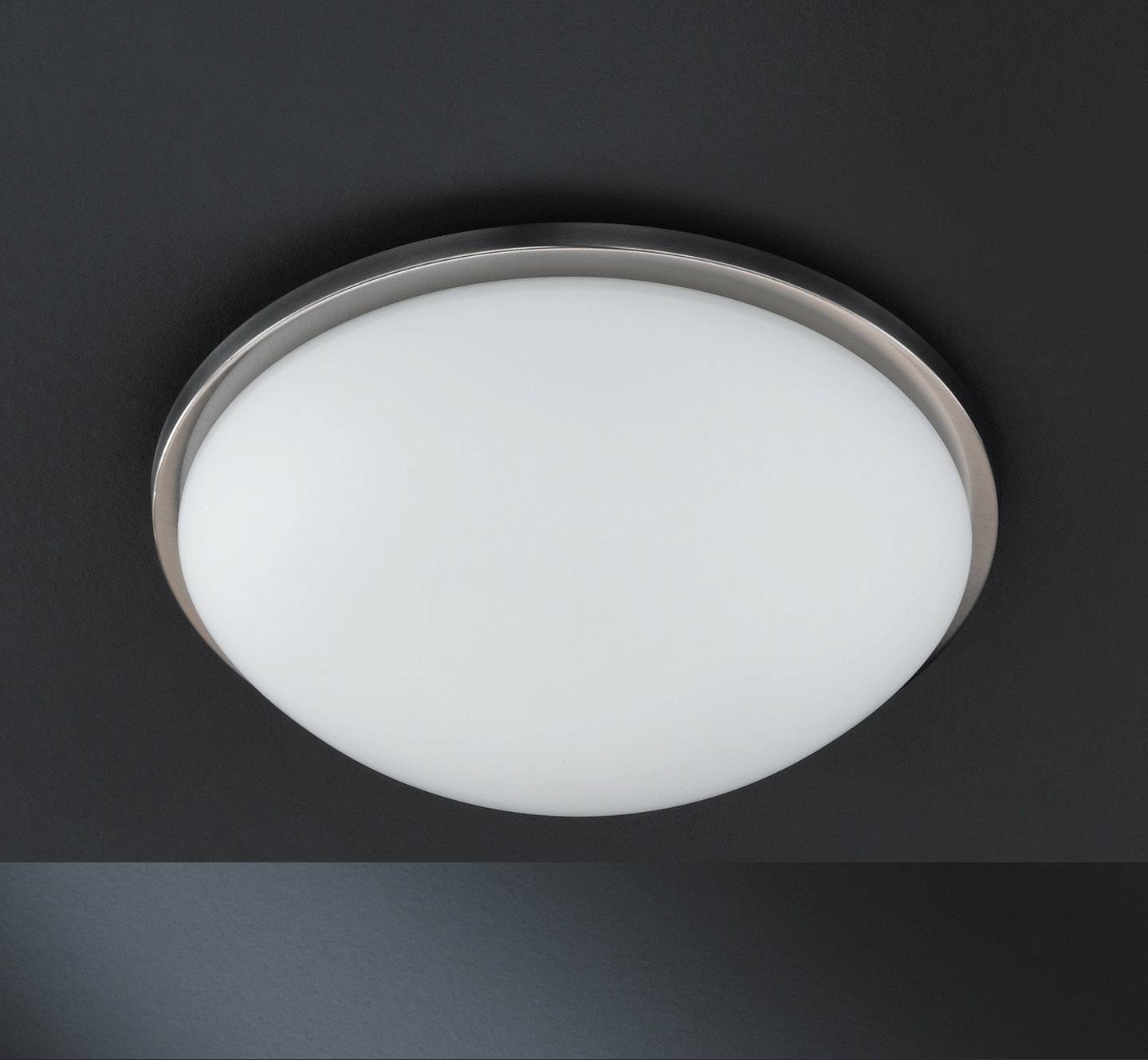 Luminaire plafonnier rond et blanc dans un environnement sombre, au design épuré et moderne.