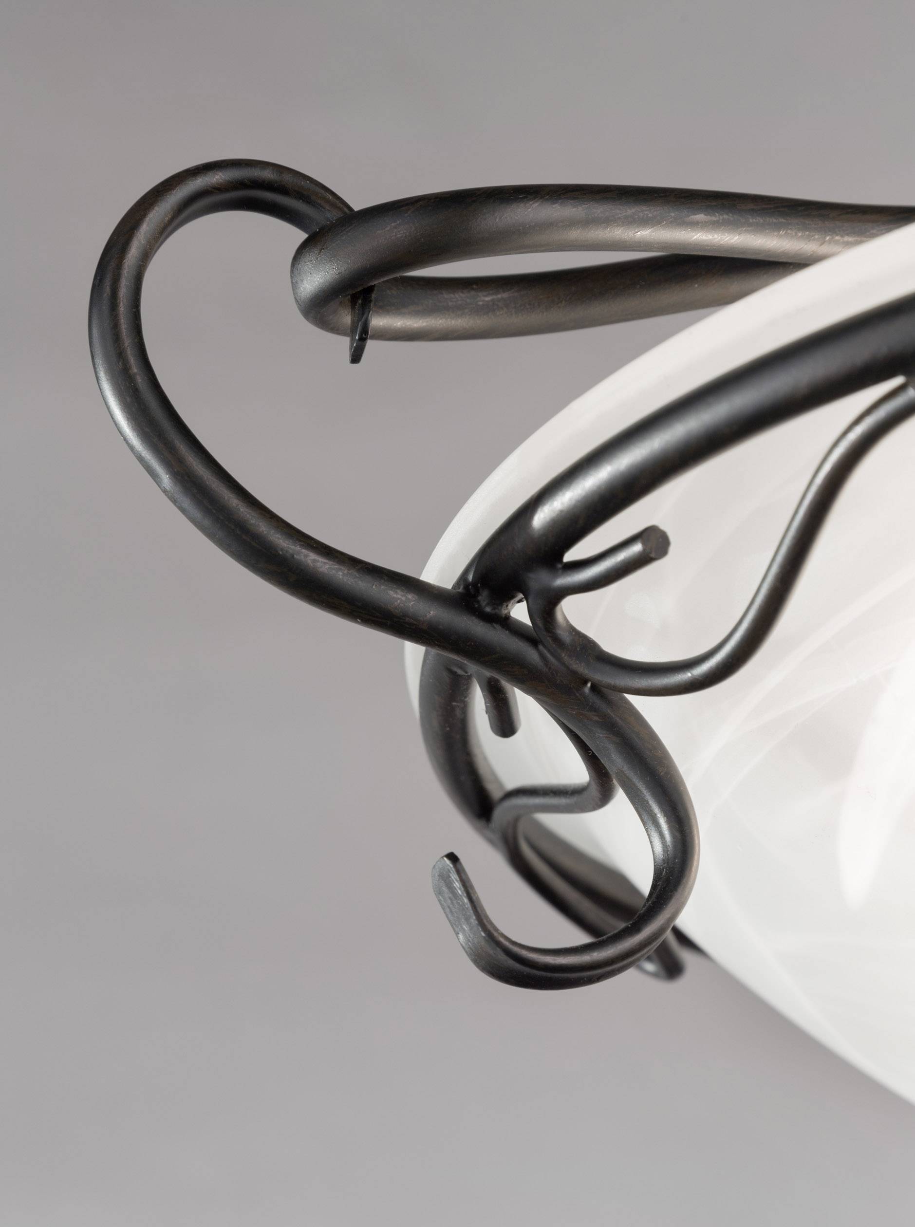 Un crochet en métal noir, artistiquement conçu, retient un tissu blanc. L'arrière-plan est gris et sobre.