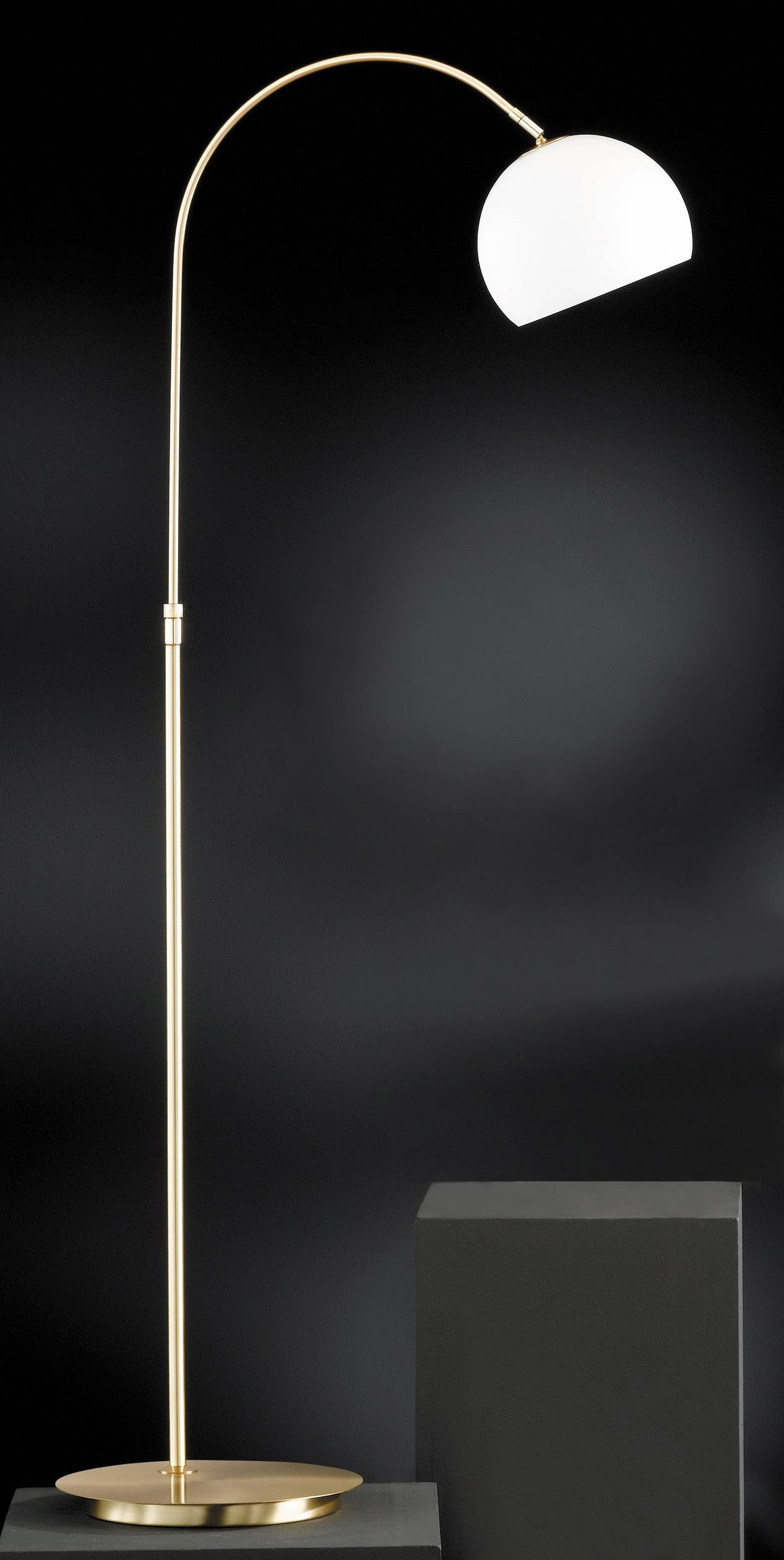 Lampadaire doré avec un col incurvé et un abat-jour semi-circulaire blanc sur un fond noir. Design minimaliste.