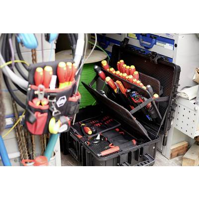 Boîte à outils contenant divers tournevis et pinces, préparée pour des installations électriques. Des rouleaux de câbles sont visibles en arrière-plan.