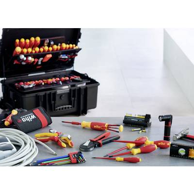 Ensemble d'outils posé sur une table, comprenant des tournevis, des pinces et un appareil de mesure. À l'arrière-plan, une mallette à outils ouverte.