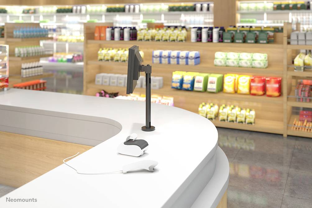 Un comptoir de caisse moderne dans un magasin avec un écran et un terminal de paiement, entouré d'étagères présentant divers produits.