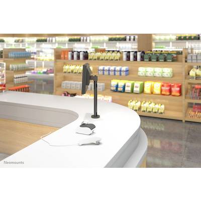 Un comptoir de caisse moderne dans un magasin avec un écran et un terminal de paiement, entouré d'étagères présentant divers produits.