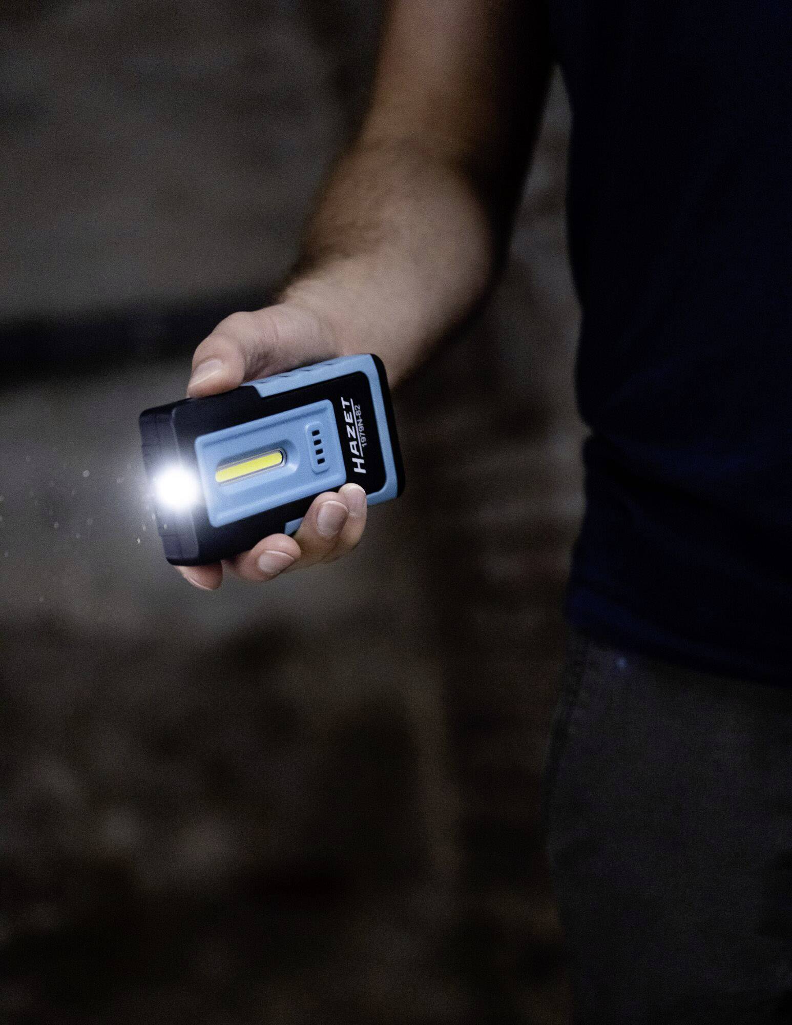 Une personne tient une petite lampe de poche lumineuse dans sa main. La lampe projette une lumière vive vers l'avant.