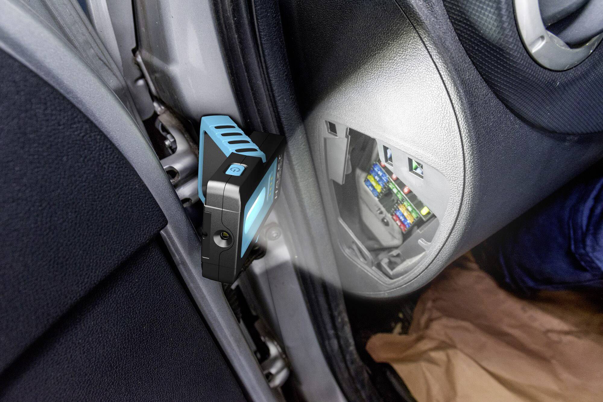 L'appareil est inséré dans un boîtier à fusibles automobile. Le boîtier à fusibles est ouvert et montre des éléments de fusibles colorés.