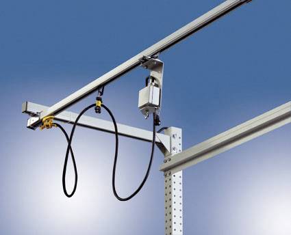 Un dispositif métallique de rails avec des câbles et des capteurs fixés sur un fond bleu, probablement une partie d'une installation industrielle.