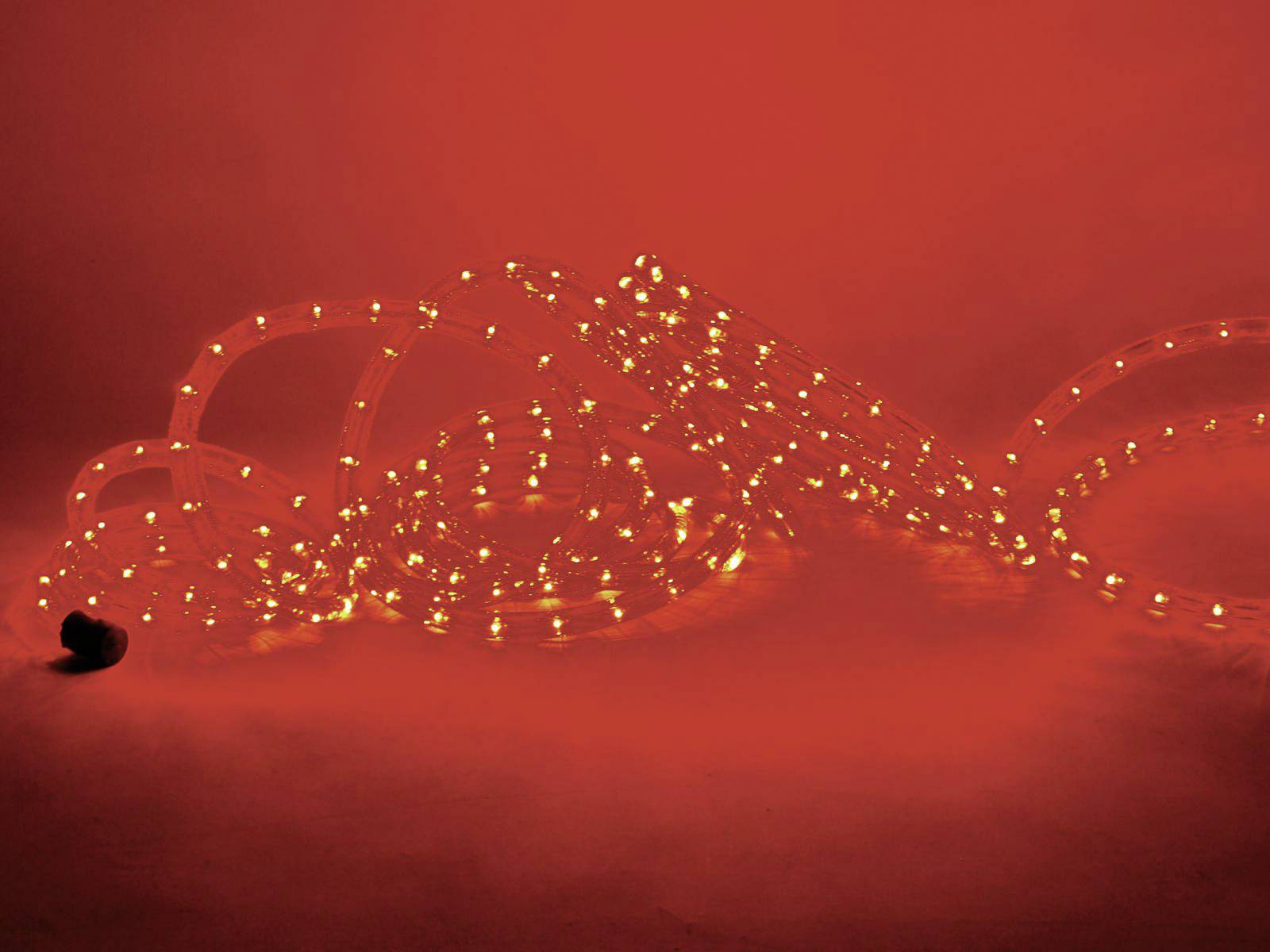 Un tube lumineux LED dans un orange chaleureux est drapé sur un fond rouge, créant un éclairage atmosphérique.