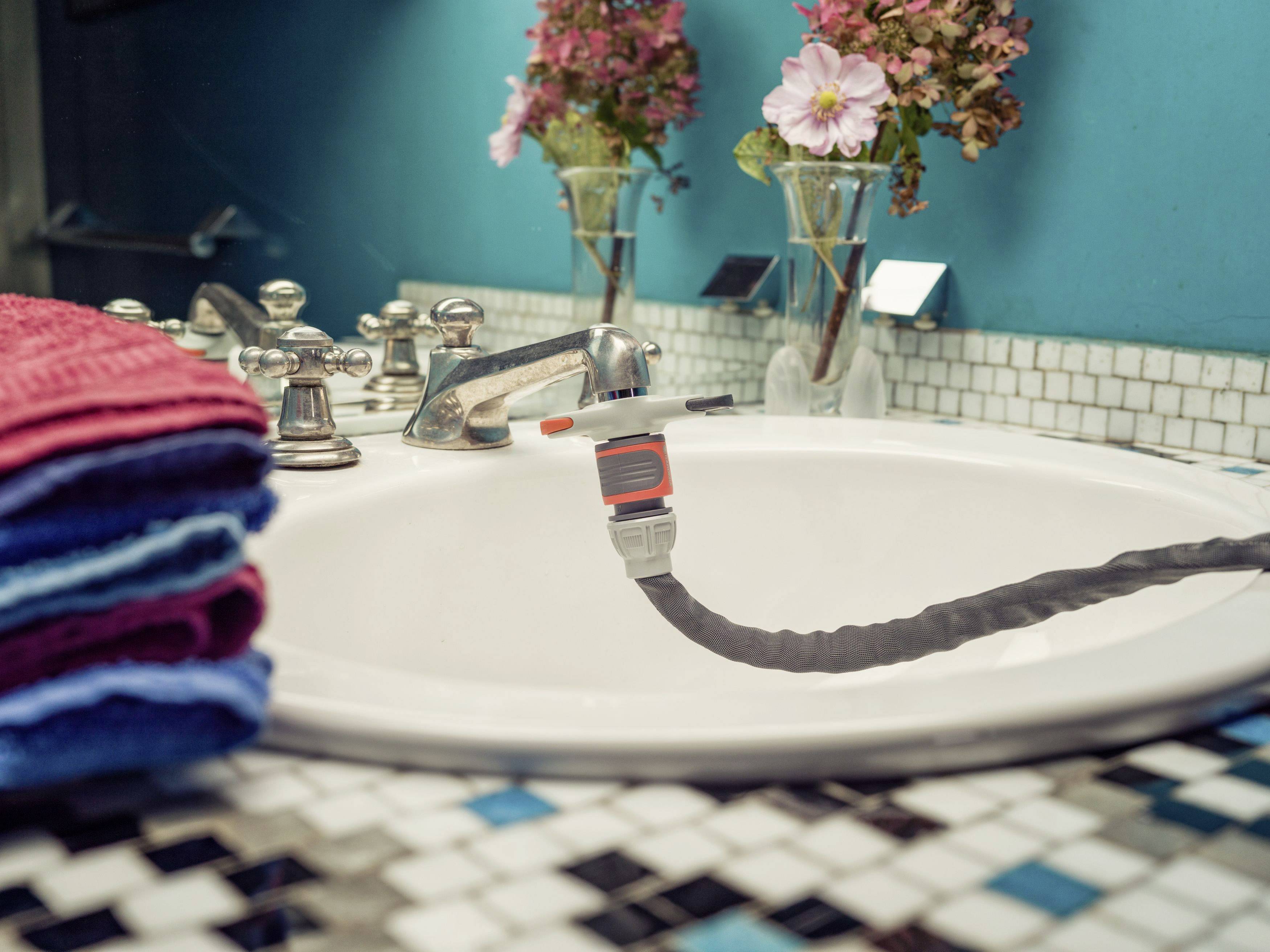 Un lavabo avec un jet d'eau coulant et un tuyau, décoré de fleurs et de serviettes.