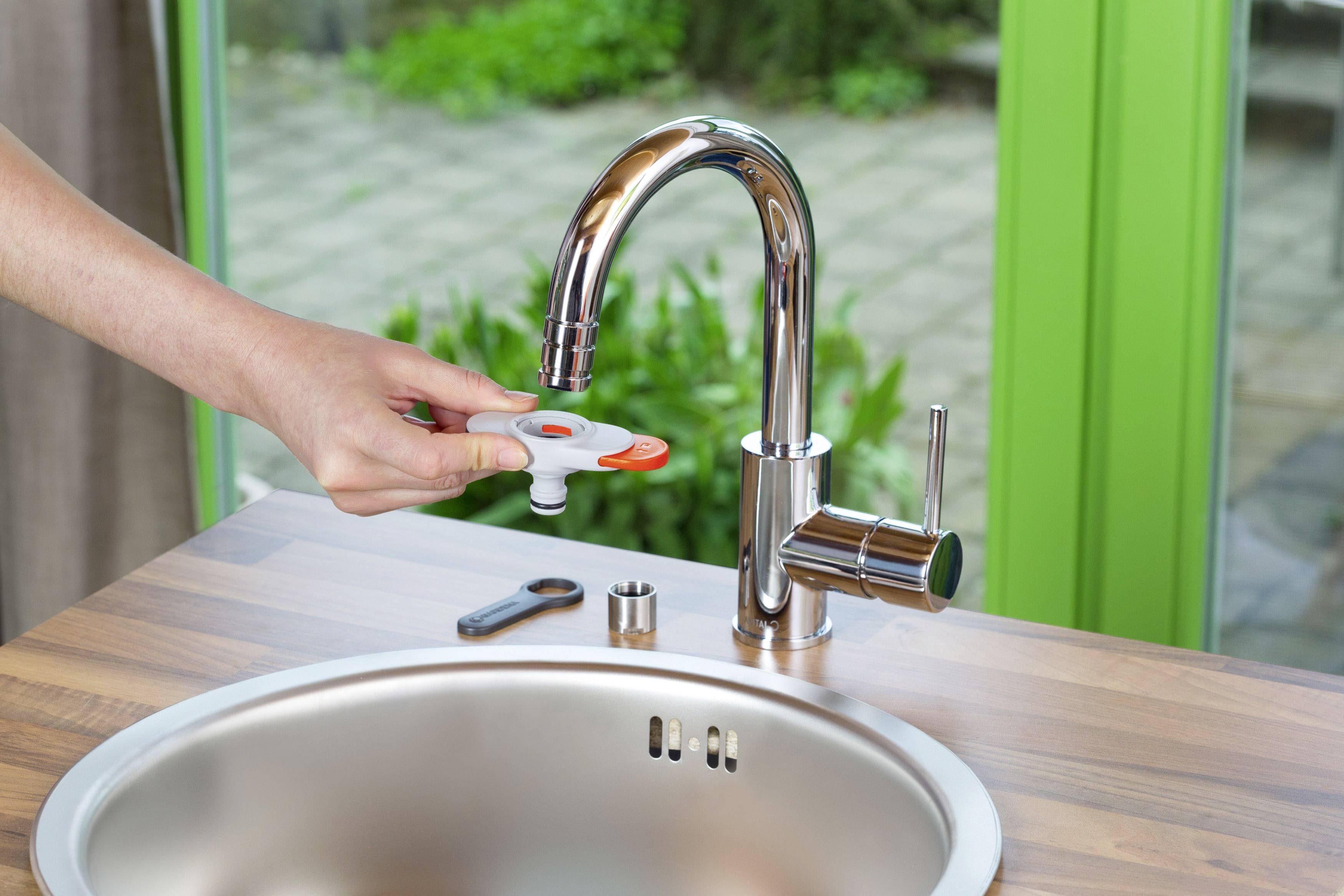 Une personne remplace le mousseur d'un robinet dans une cuisine moderne afin d'économiser de l'eau.