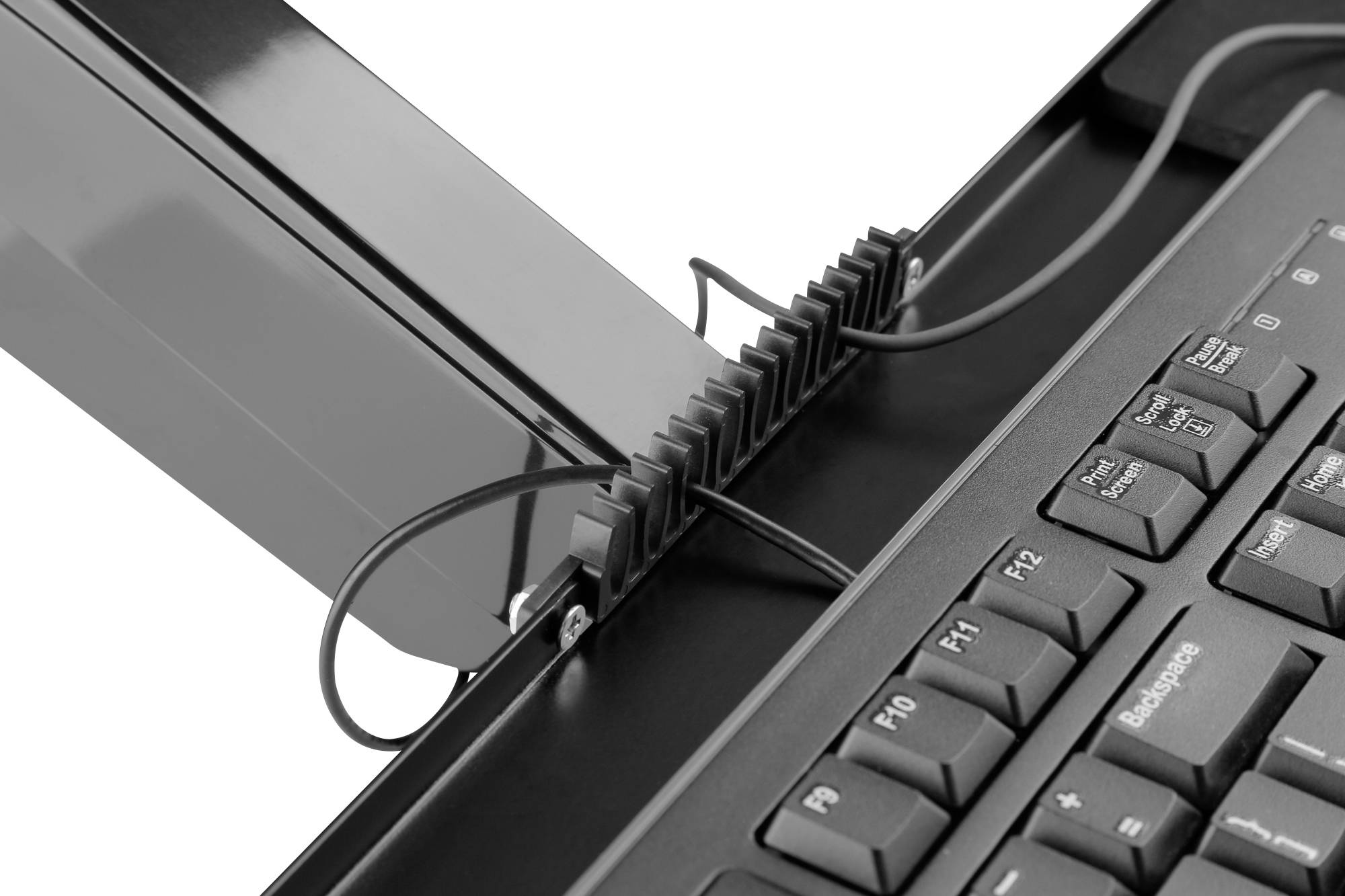 Vue rapprochée d'un clavier d'ordinateur avec des câbles acheminés par un dispositif de gestion de câbles.