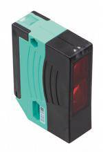 Un capteur rectangulaire noir et vert avec une lumière rouge sur un côté, souvent utilisé pour des applications industrielles.
